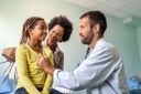 A-cheerful-girl-with-her-mother-and-a-male-family-medicine-doctor-wearing-a-stethoscope-during-her-routine-health-screenings.jpg